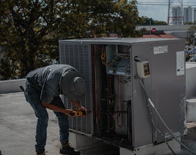 HVAC technician performing detailed maintenance on rooftop unit